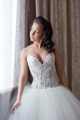 Fototapeta premium Pretty young bride posing by window in hotel room