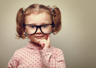 Thinking little kid girl looking happy in glasses