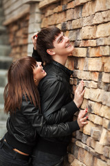 Fototapeta na wymiar Happy young couple in leather jackets at the brick wall