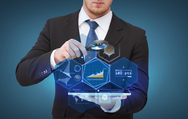 businessman hand holding magnifier over tablet pc