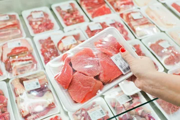 Crédence de cuisine en verre imprimé Viande Viande emballée avec une main de femme au supermarché