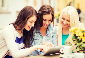 beautiful girls looking at tablet pc in cafe
