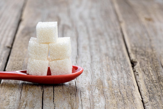 Sugar Cubes In Spoon On Wooden Background