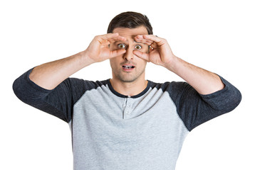 Surprised young man looking through hand binoculars