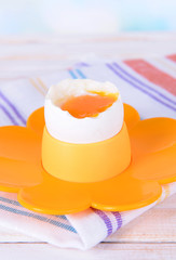 Boiled egg in egg cup on table on light background