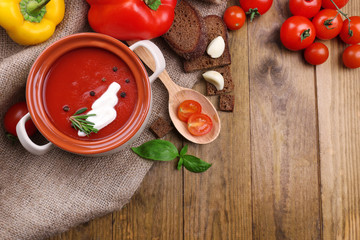 Tasty tomato soup and vegetables on wooden table