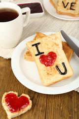 Delicious toast with jam and cup of tea on table close-up