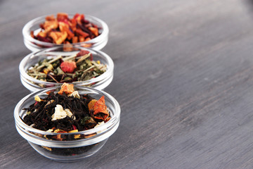 Aromatic dry tea in bowls on wooden background
