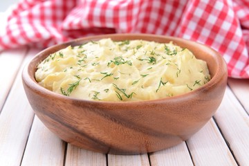 Delicious mashed potatoes with greens in bowl on table close-up