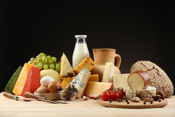 Tasty dairy products on wooden table, on dark background
