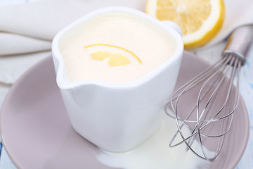 Delicate sauce in pitcher on wooden table close-up