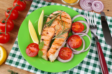 Tasty grilled salmon with vegetables, on wooden table