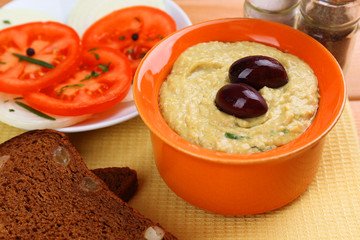 Bowl of tasty fresh hummus with olives