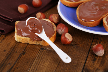 Bread with sweet chocolate hazelnut spread on plate on table