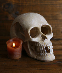 Skull and candle on wooden background