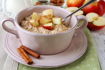 Tasty oatmeal with apples and cinnamon on table close up