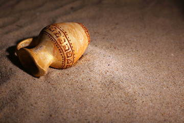 Greek ceramic amphora on sand, close up