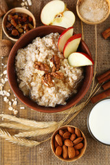 Tasty oatmeal with nuts and apples on wooden table