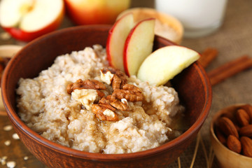 Tasty oatmeal with nuts and apples on table close up