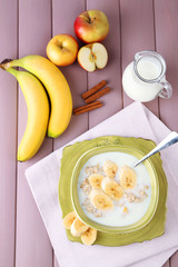 Tasty oatmeal with bananas and milk on wooden table