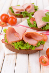 Delicious sandwiches with lettuce and ham on table close-up