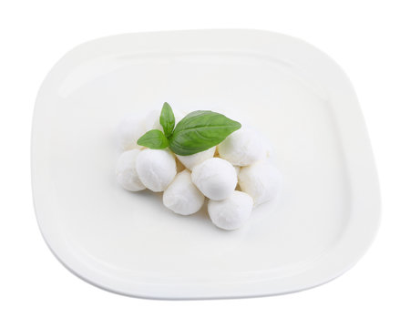 Tasty mozzarella cheese with basil on plate isolated on white