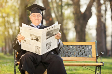 Mature college professor reading newspaper in park
