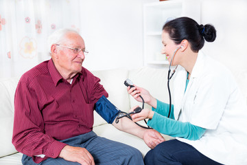 Young Doctor Measuring Blood Pressure Of Senior Patient