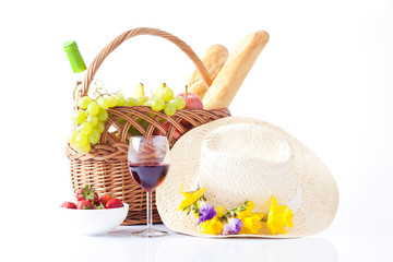 picnic basket with bottle of wine,fruits, bread and summer hat
