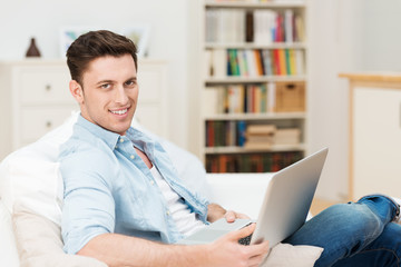 mann sitzt auf dem sofa mit seinem notebook