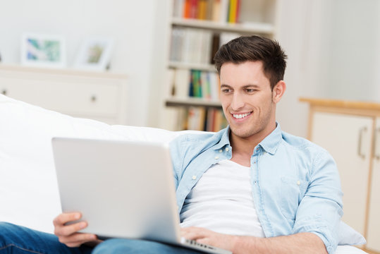 junger mann mit laptop auf dem sofa