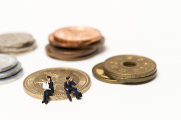 お金の硬貨の上に座って仕事に悩む人間