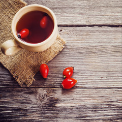 cup of tea with hip roses, on wooden table