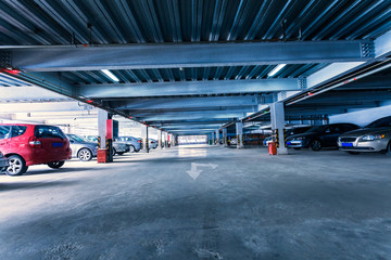 Parking garage, interior with a few parked cars.
