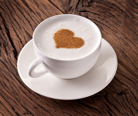 Cup of cappuccino with ground cinnamon in the form of heart.