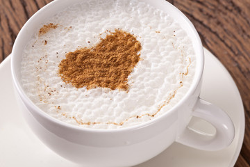 Cup of cappuccino with ground cinnamon in the form of heart.