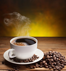Cup of coffee with coffee beans near it.