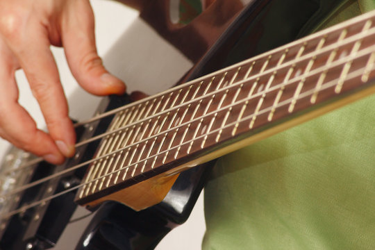 Guitarist playing the electric bass guitar closeup