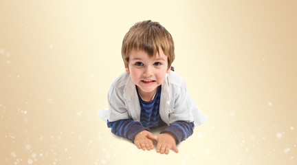 Cute blonde kid on the floor over ocher background