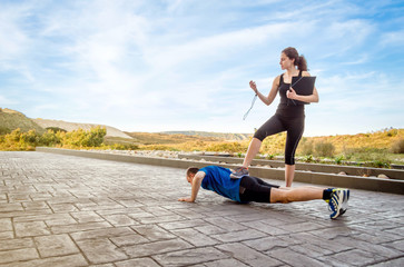 Girl coach training hard a man through push ups