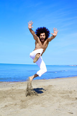Man having fun jumping on sand in front of the ocean in vacation