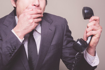 Naklejka premium Businessman on phone covering his mouth