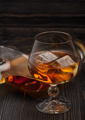 Whiskey with ice on dark wooden background