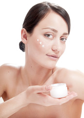 Beautiful woman applying cosmetic cream treatment on her face.