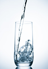 water pouring into glass on blue background