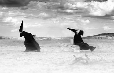 Two strange persons in black cloaks traveling in the desert