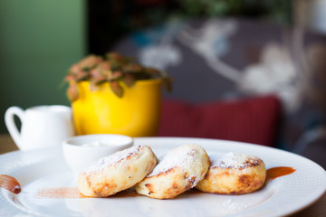 Cheese pancakes with sour cream on a white plate. Breakfast