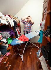 housewife having headache of big pile of not ironed clothes