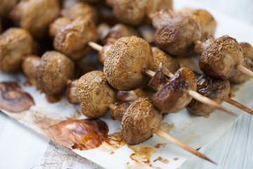 Champignon kebabs on a baking paper, close-up, horizontal shot