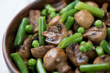 Close-up of roasted champignons with peas and beans, studio shot